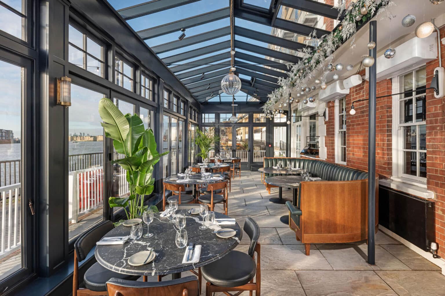 Modern bar and restaurant interior inside a light-filled conservatory.