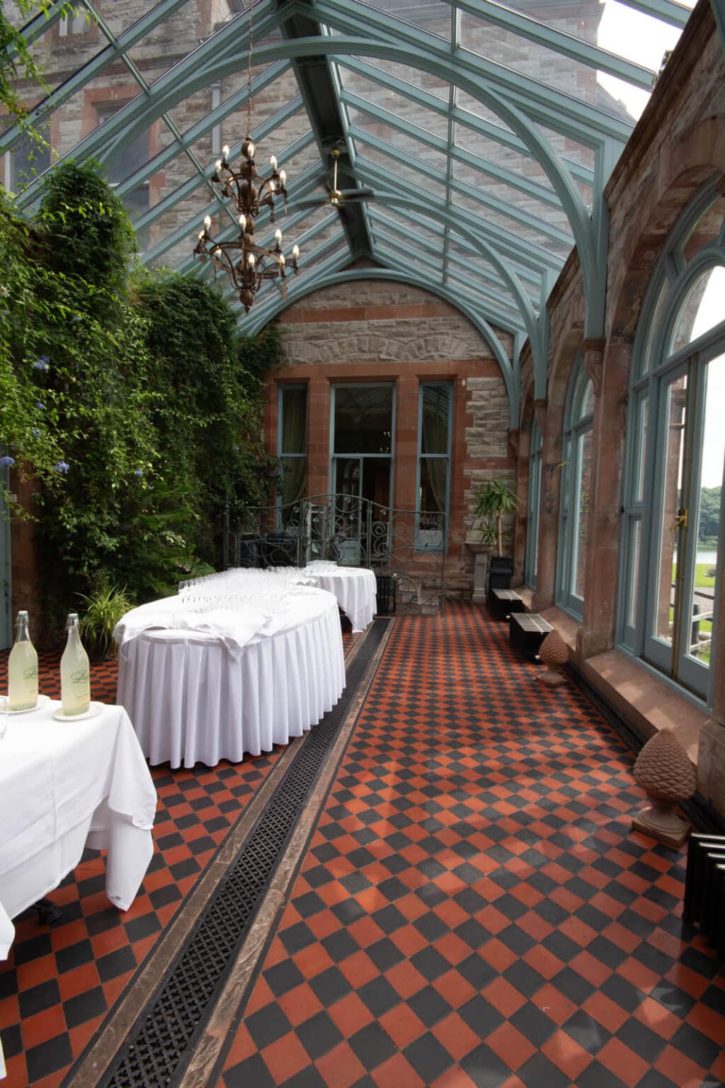 Narrow conservatory restaurant set for a private dining event.