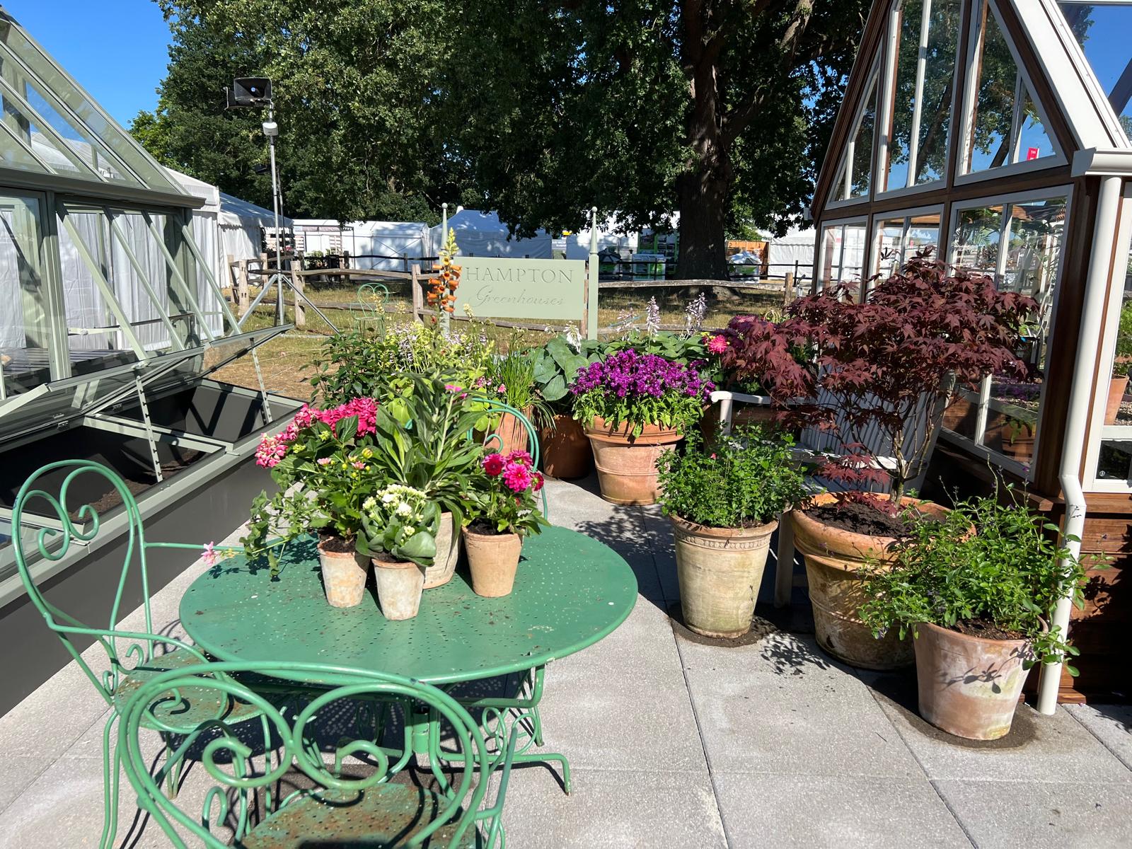 Various plants and flowers in pots, placed around the Hampton greenhouse model.