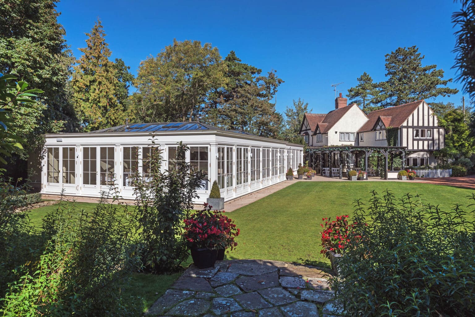 Large white conservatory for a commercial wedding venue, in a garden.